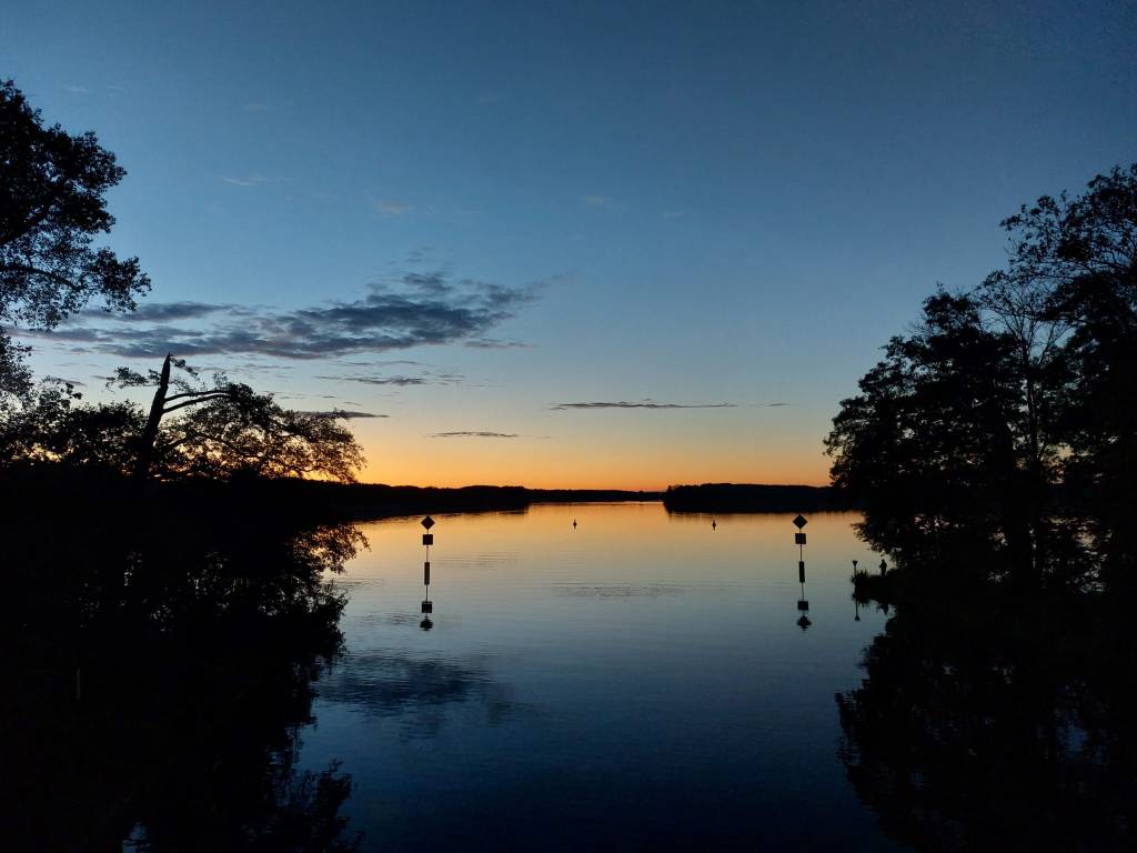 Ein Hintergrund der einen See mit Sonnenuntergang darstellt